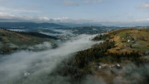 Aerial view of a misty valley in Yablunytsya, with rolling hills and forested landscape.