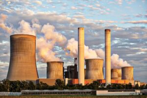 View of a power plant with smoke emissions under a cloudy sky, depicting industrial energy production.