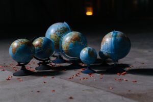 A collection of globes arranged on a concrete floor, surrounded by scattered petals.