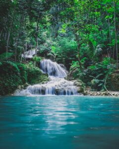 Captivating tropical waterfall cascading through vibrant jungle greenery, a serene nature escape.