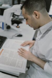 A focused scientist reads a book in a modern laboratory environment.