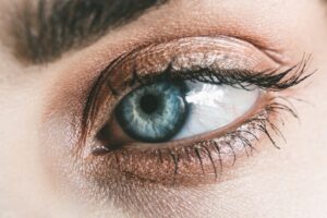 Detailed close-up of a woman's blue eye, showcasing makeup and eyelashes.